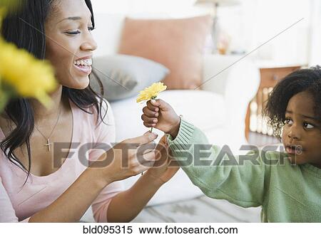 Stock Photography - African American boy giving mother flower. Fotosearch