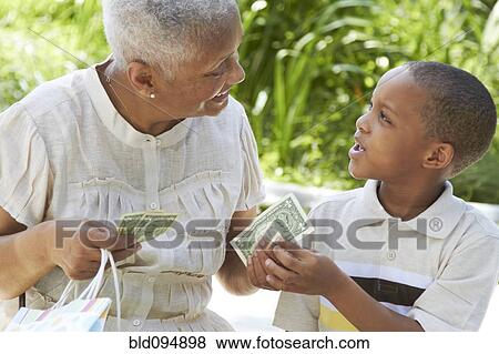Stock Photo - African American grandmother handing money to grandson. Fotosearch