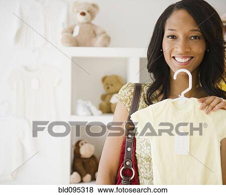 Stock Photo - African American woman holding baby clothing. Fotosearch