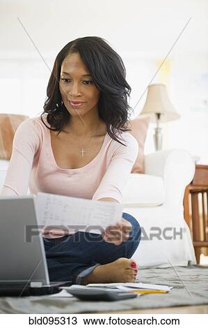 Stock Image - African American woman paying bills online. Fotosearch