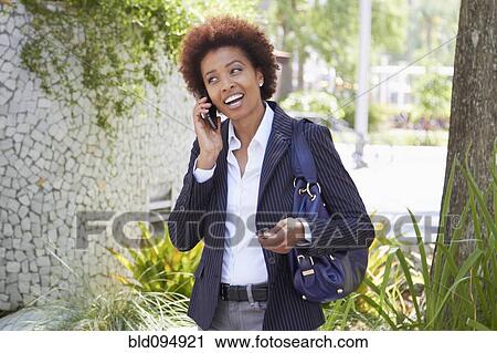 Stock Image - African American woman talking on cell phone outdoors. Fotosearch