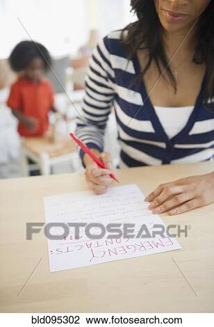 Stock Image - African American woman writing out contact phone numbers. Fotosearch