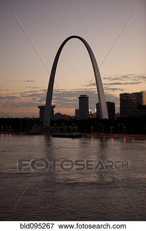 Stock Photo - Arch landmark next to urban river at sunset. Fotosearch