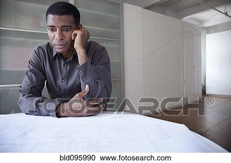 Stock Image - Black businessman reviewing blueprints. Fotosearch