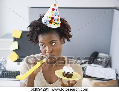 Black businesswoman blowing party blower at desk View Large Photo Image Stock Image - Black businesswoman blowing party blower at desk. Fotosearch