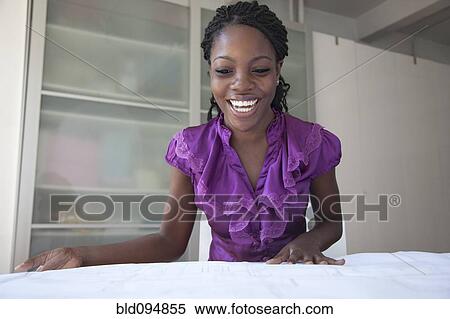 Stock Photography - Black businesswoman reviewing blueprints. Fotosearch