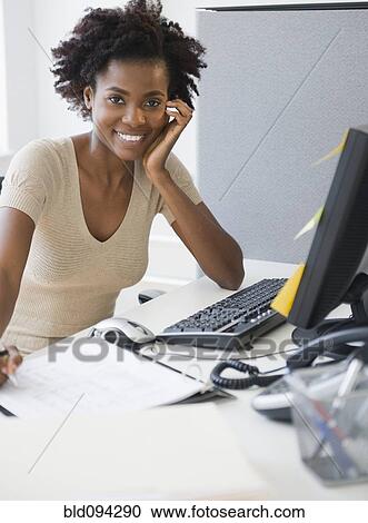 Stock Image - Black businesswoman working at desk. Fotosearch