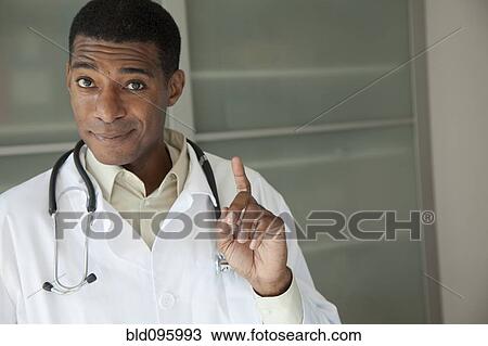 Black doctor in lab coat with hand raised View Large Photo Image Stock Image - Black doctor in lab coat with hand raised. Fotosearch