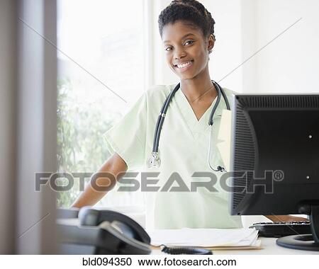 Black nurse standing at desk View Large Photo Image Stock Image - Black nurse standing at desk. Fotosearch