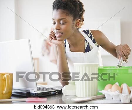 Black woman cooking and looking at recipe on laptop View Large Photo Image Stock Image - Black woman cooking and looking at recipe on laptop. Fotosearch