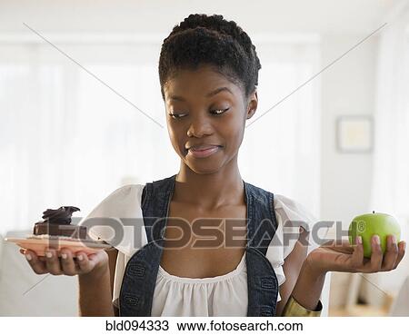 Black woman deciding between chocolate cake and apple View Large Photo Image Stock Image - Black woman deciding between chocolate cake and apple. Fotosearch