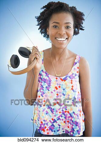 Picture - Black woman holding headphones. Fotosearch