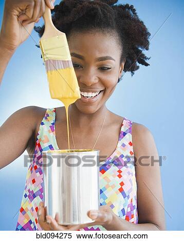 Stock Photography - Black woman holding paintbrush dripping paint. Fotosearch