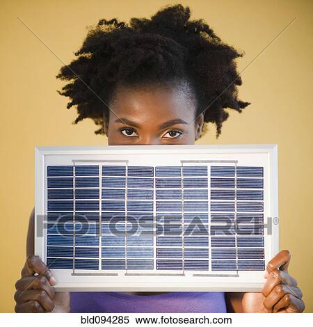 Stock Photography - Black woman holding solar panel. Fotosearch