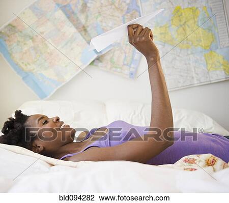 Black woman laying in bed holding paper airplane View Large Photo Image Stock Image - Black woman laying in bed holding paper airplane. Fotosearch