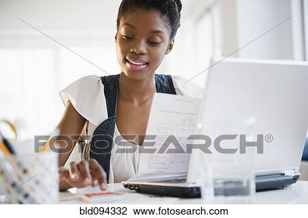 Stock Image - Black woman paying bills online. Fotosearch
