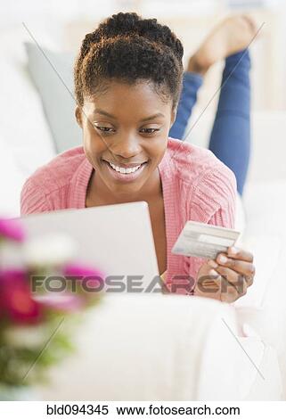 Stock Photography - Black woman shopping online with credit card. Fotosearch