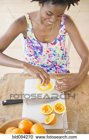 Stock Image - Black woman squeezing fresh orange juice. Fotosearch