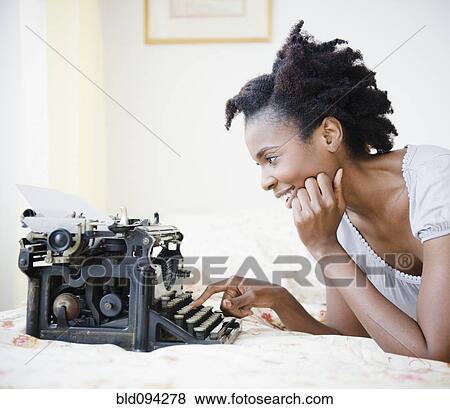 Stock Photo - Black woman using old-fashioned typewriter. Fotosearch
