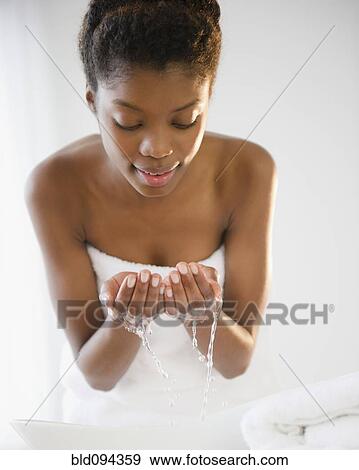 Stock Photo - Black woman washing her face. Fotosearch