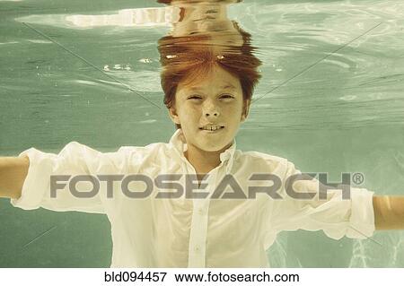 Stock Photo - Boy in shirt swimming underwater in swimming pool. Fotosearch