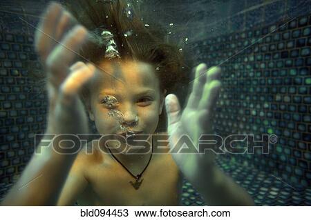 Stock Image - Boy swimming underwater in swimming pool. Fotosearch