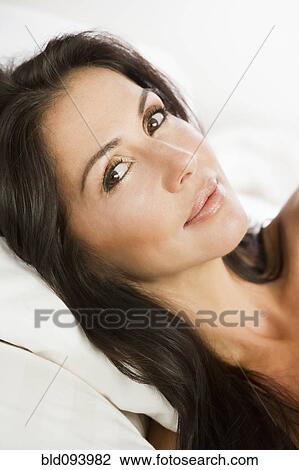 Stock Image - Brazilian woman laying in bed. Fotosearch
