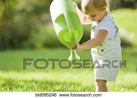 Stock Photograph - Caucasian baby lifting watering can. Fotosearch