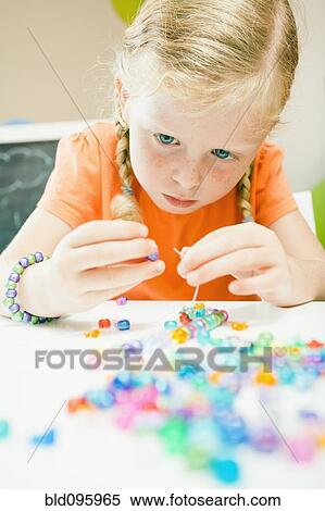 Stock Photography - Caucasian girl stringing beads. Fotosearch