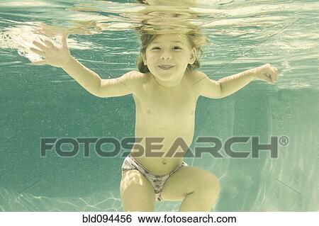 Stock Photograph - Caucasian girl swimming underwater in swimming pool. Fotosearch