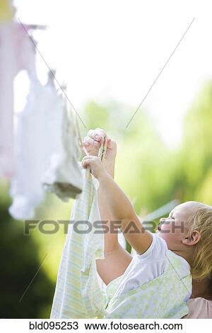 Stock Image - Caucasian mother and baby hanging laundry on clothes line. Fotosearch