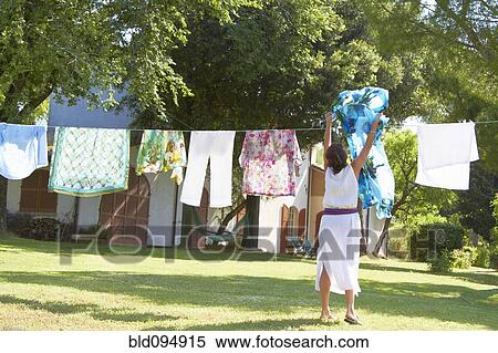 Stock Photography - Caucasian woman hanging laundry on clothes line. Fotosearch