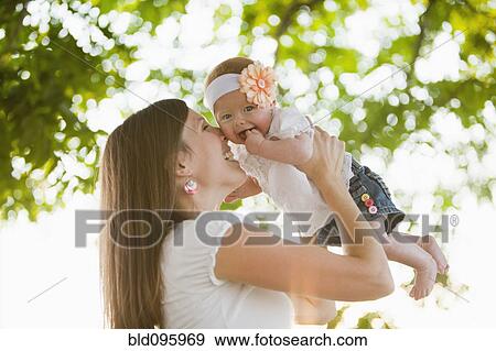 Stock Photo - Caucasian woman holding baby girl outdoors. Fotosearch