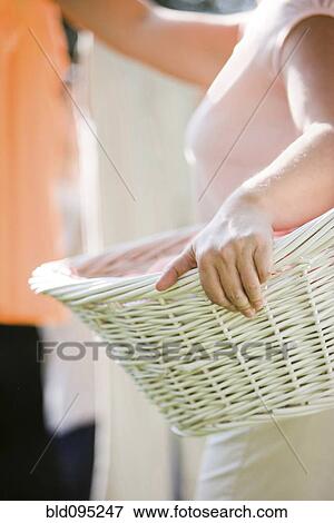 Stock Photo - Caucasian woman holding basket and hanging laundry. Fotosearch