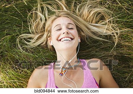 Caucasian woman laying in grass listening to music View Large Photo Image Picture - Caucasian woman laying in grass listening to music. Fotosearch