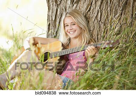 Stock Photo - Caucasian woman playing guitar outdoors. Fotosearch