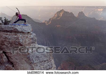 Picture - Caucasian woman practicing yoga on cliff near canyon. Fotosearch