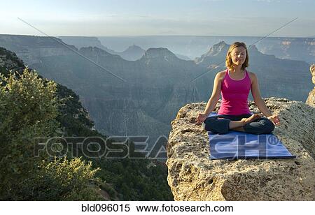 Stock Photography - Caucasian woman practicing yoga on cliff near canyon. Fotosearch