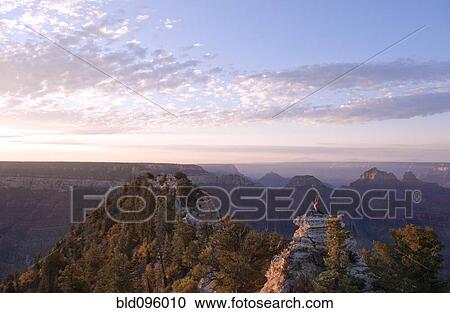 Stock Image - Caucasian woman practicing yoga on top of rock formation. Fotosearch