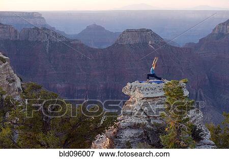 Stock Photo - Caucasian woman practicing yoga on top of rock formation. Fotosearch