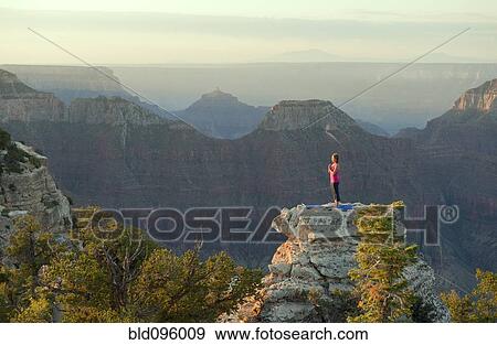 Stock Photo - Caucasian woman practicing yoga on top of rock formation. Fotosearch
