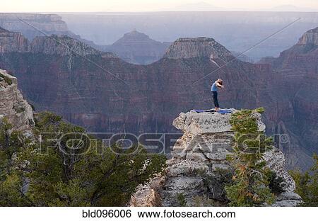 Stock Photograph - Caucasian woman practicing yoga on top of rock formation. Fotosearch