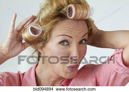 Picture - Caucasian woman putting rollers in her hair. Fotosearch