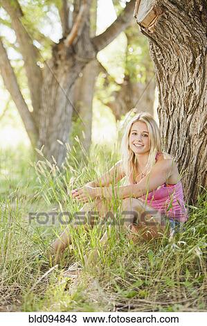 Stock Image - Caucasian woman sitting in grass. Fotosearch