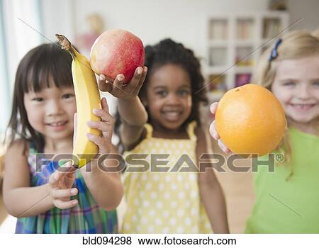 Stock Photo - Children holding out fresh fruit. Fotosearch