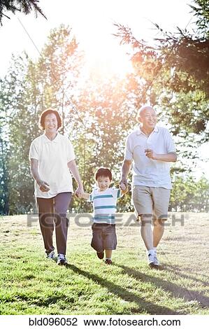 Stock Image - Chinese grandparents holding hands with grandson. Fotosearch