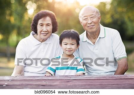 Picture - Chinese grandparents sitting outdoors with grandson. Fotosearch