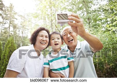 Stock Photo - Chinese grandparents taking self-portrait with grandson. Fotosearch