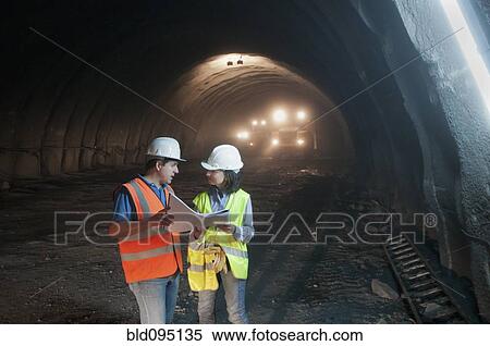 Construction workers looking at blueprint in tunnel View Large Photo Image Stock Photography - Construction workers looking at blueprint in tunnel. Fotosearch