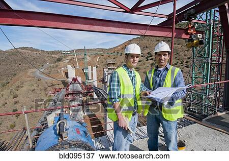 Stock Photo - Construction workers standing at construction site. Fotosearch